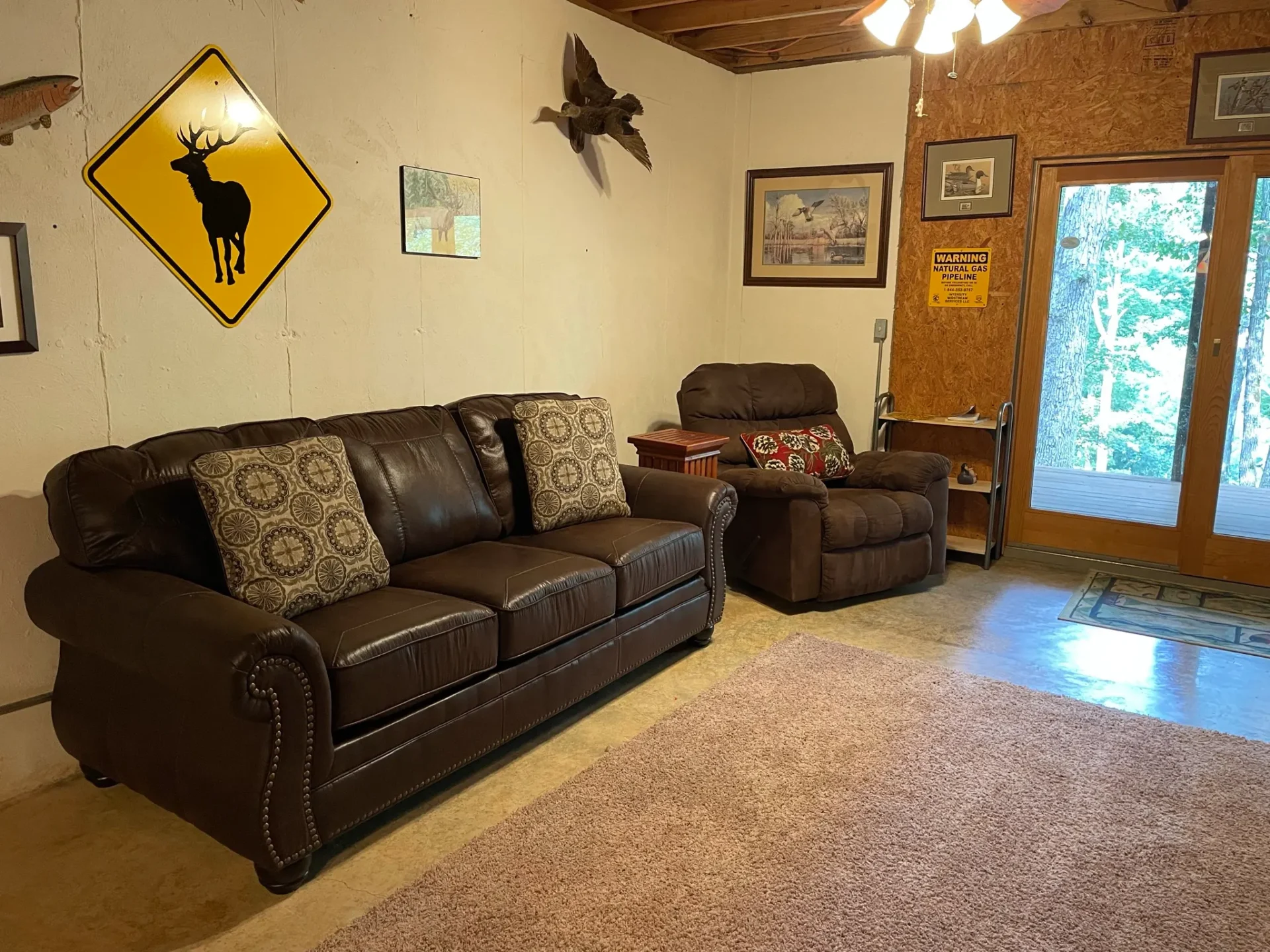 A living room with brown leather furniture and a rug.