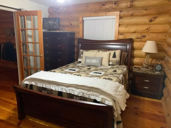 A bedroom with wood walls and wooden floors.