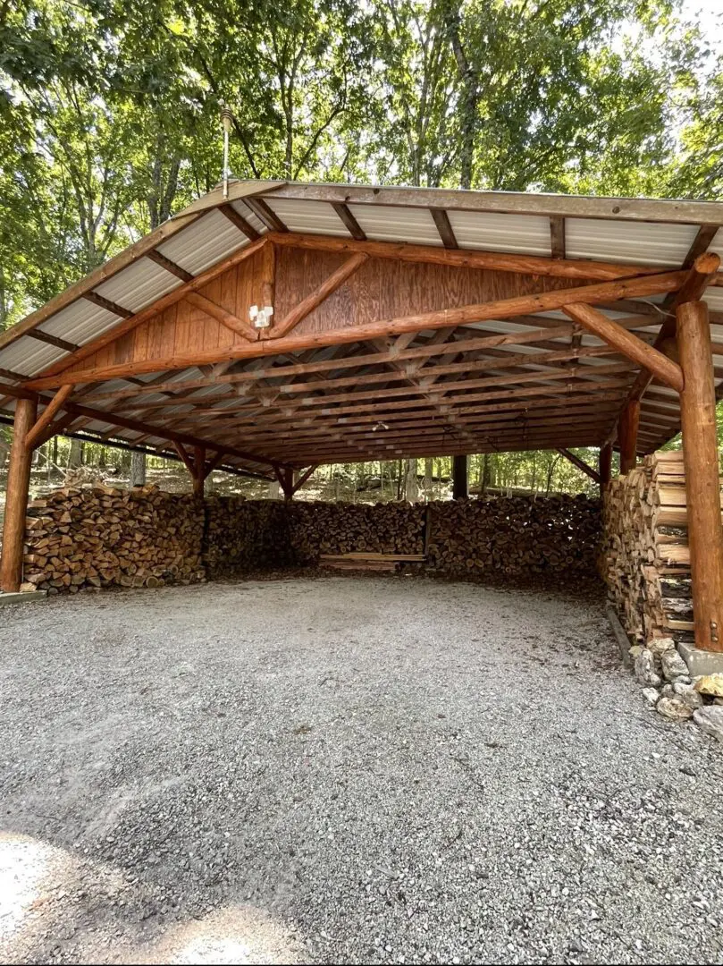 A large wooden shed with wood stacked on top of it.