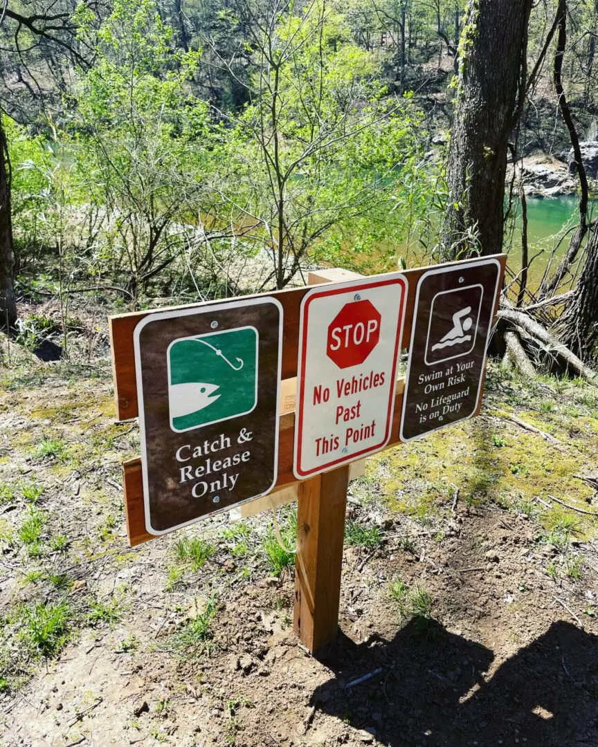 A group of signs on a post in the woods.