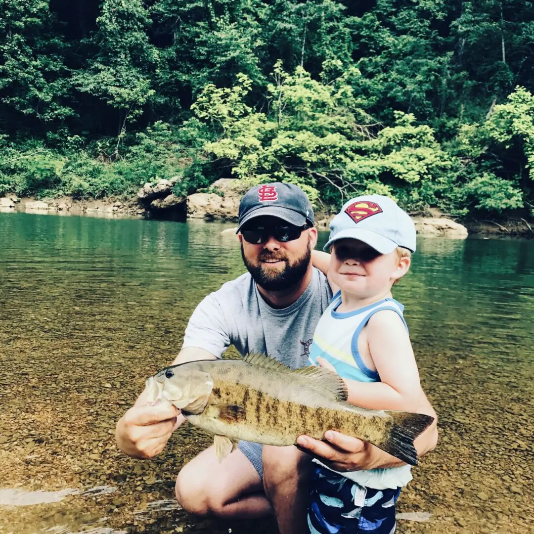 A man and boy holding a fish in the water.