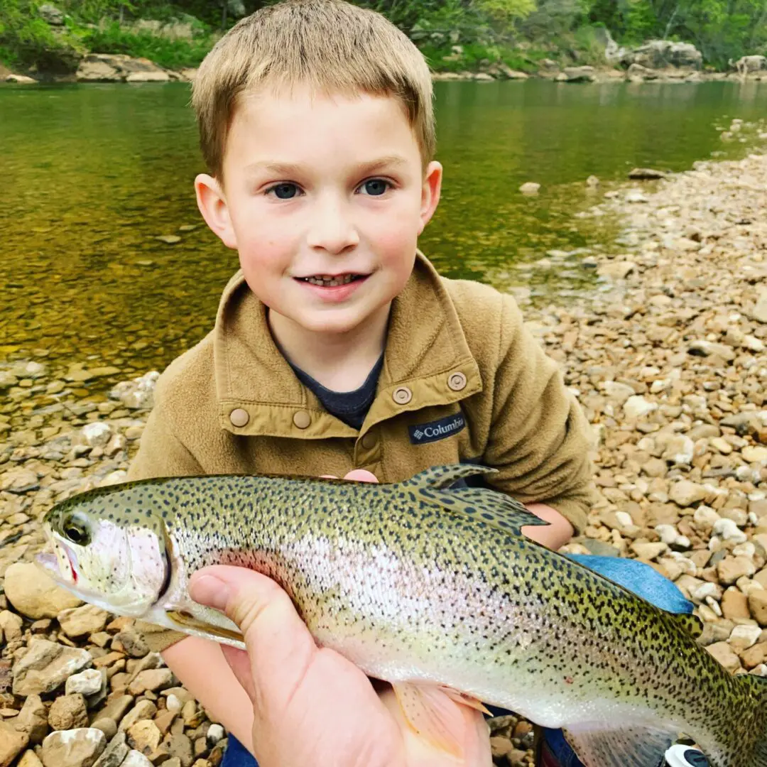 A young boy holding a fish while sitting on the ground.