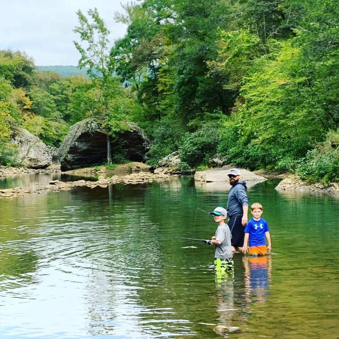 A man and two boys fishing in the water.