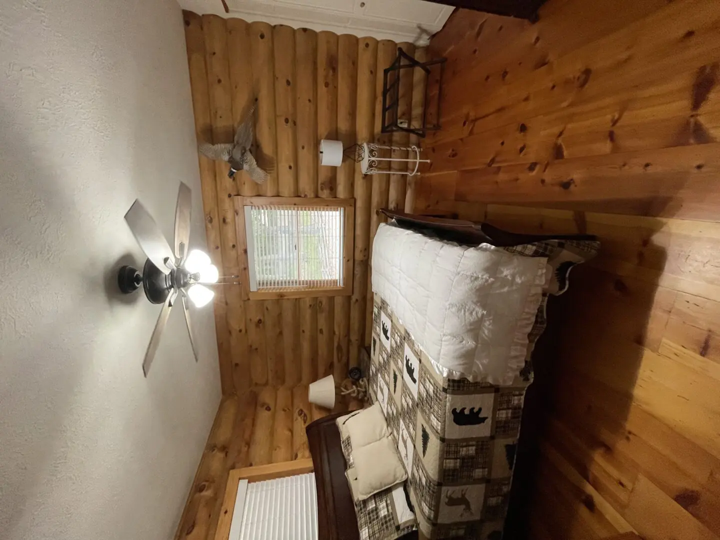 A bedroom with wood floors and a ceiling fan.